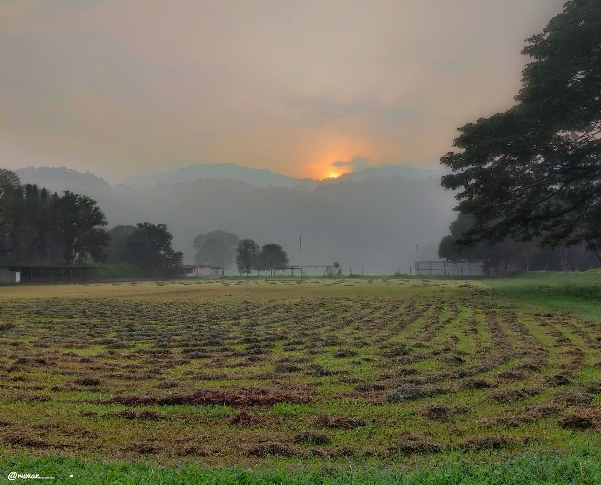 The playing field at the University of Peradeniya, Sri Lanka, at sunset in 2019: cut grass, the goalposts at the far end, and the hills behind them.