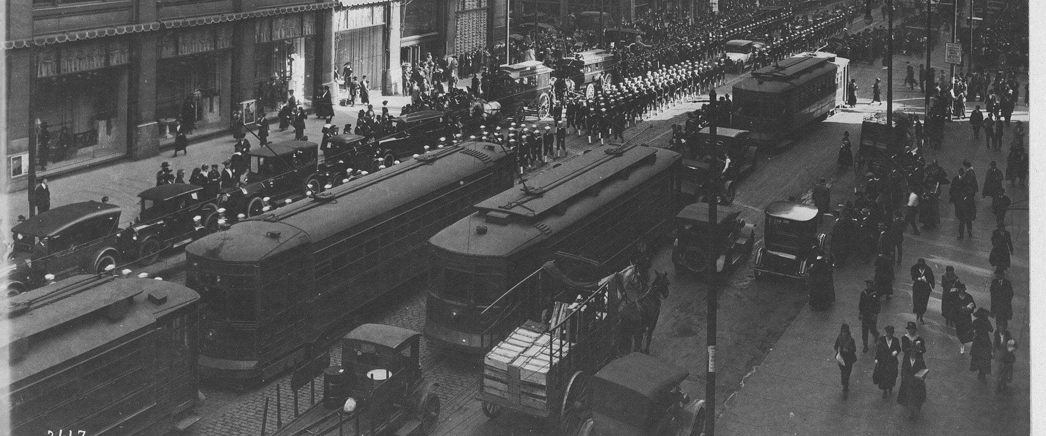 State Street, Chicago, photographed in 1917 or 1918: streetcars, delivery wagons and a column of sailors outside the department stores.